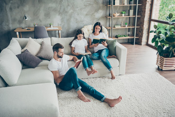Nice attractive lovely charming friendly focused cheerful cheery idyllic family wearing casual white t-shirts jeans reading book hobby at industrial loft style interior living-room indoor