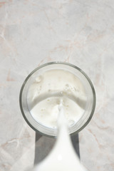 Flowing milk. Close-up of milk stream pouring into glass, top view