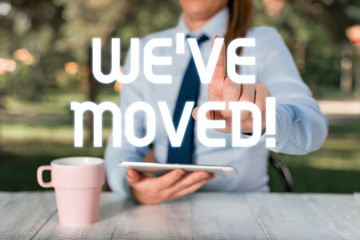 Text sign showing We Ve Moved. Business photo text having strong feelings sadness or sympathy has said or done Female business person sitting by table and holding mobile phone