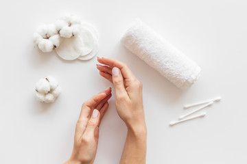 Cotton flowers with pads, swabs, hands on white background top view