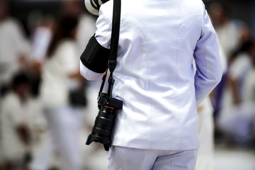 Professional cameraman back hanging strap and mirrorless camera with blur crowd background.