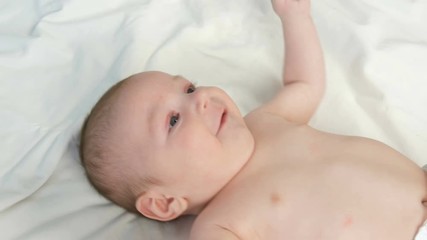 Portrait of beautiful funny little newborn baby of two months lying on a white bed