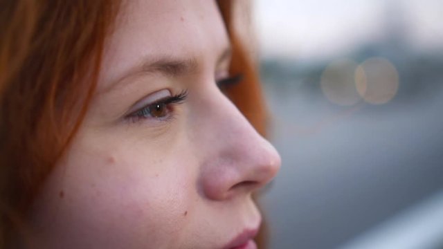 Сlose up Portrait of Beautiful Young Redhead Woman Exploring Spirituality Contemplating Future with Wind Blowing Hair city traffic on the background