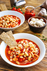 Tasty beans with tomato sauce in bowl on wooden table