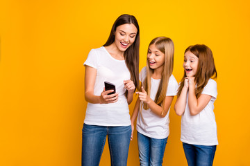 Obraz premium Photo of three pretty ladies holding telephone watching humor video wear casual clothes isolated yellow background