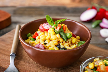 Bowl with tasty boiled legumes, vegetables and sausages on table