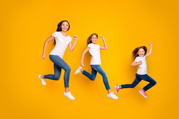 Fototapeta na wymiar Full body photo of three ladies jumping high hurrying sale shopping wear casual clothes isolated yellow background