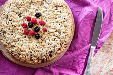 Homemade shortcrust berry pie with crumble on wooden board