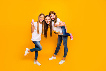 Obraz premium Photo of funky three ladies showing v-sign spending leisure time wear casual clothes isolated yellow background
