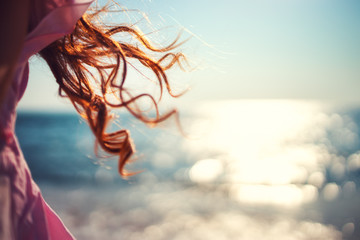 Little girl, kid playing on the beach with wind in her hair