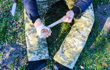 Man is putting bandage on bleeding wound. Injured hand. Cut with a knife. Tourist in the nature....
