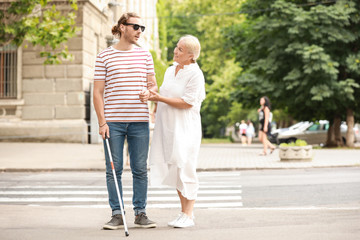 Blind young man with mother walking outdoors