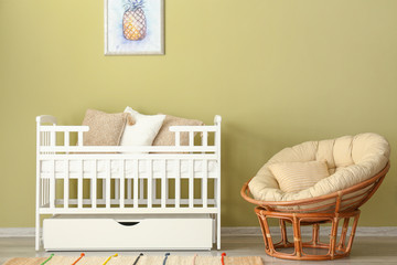 Stylish baby bed near color wall in interior of children's room