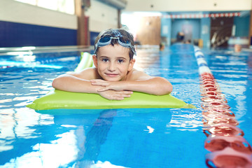 The boy smiles in the swimming pool.