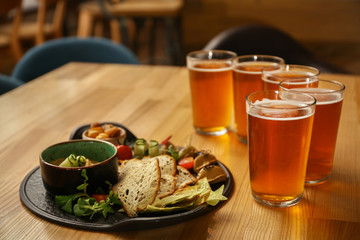 Glasses of fresh beer and snacks on table in pub