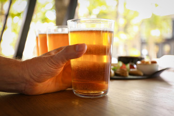 Man drinking fresh beer in pub, closeup