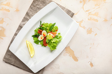 Plate of tasty fresh salad with quail eggs on light background