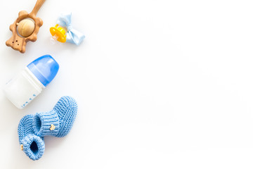 Blue knitted footwear for kids, dummy, rattle and bottle on white background top view space for text