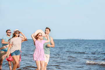 Happy friends running on sea beach at resort