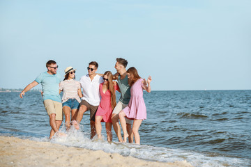 Happy friends on sea beach at resort