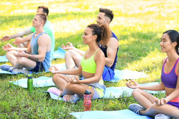 Fototapeta premium Group of young sporty people meditating together outdoors