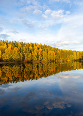 Amazing colors in the nature during sunny autumn day in Finland. Colorful forest and reflection in the calm water.