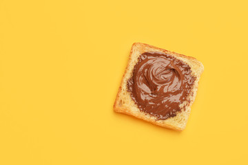 Tasty toasted bread with chocolate paste on color background
