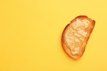 Tasty toasted bread with peanut butter on color background