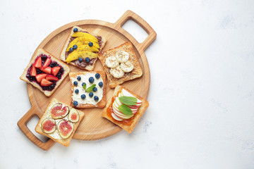 Board with tasty sandwiches on light background