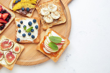 Fototapeta na wymiar Board with tasty sandwiches on light background