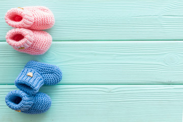 Knitted blue and pink footwear for baby on mint green wooden background top view mockup