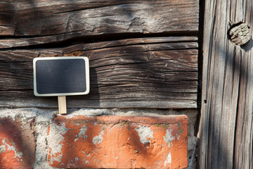 An information sign stands on a brick and wooden obsolete wall