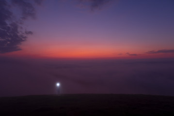 Fototapeta premium mountaineer with headlamp and walking on the mountain in the fog at dusk, Aiako Harriak natural park