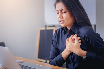 Working woman face suffering and holding breast because of heart infarction in office.