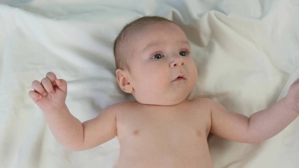 Portrait of beautiful funny little newborn baby of two months lying on a white bed