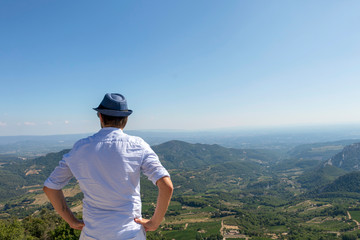 Fototapeta na wymiar Young handsome man travel back view in mountains, caucasian male traveler in Provence in Vaucluse, France
