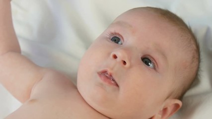 Portrait of beautiful funny little newborn baby of two months lying on a white bed