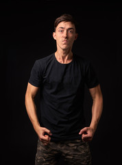 Fototapeta premium Angry and irritable man stands in the studio on a dark background