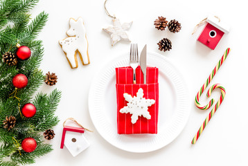 Table setting for new year with pine branch, decorations, candy cane, plate and tableware white background top view
