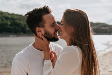 Happy couple in love hugging and kissing together on the beach in warm sunny day.