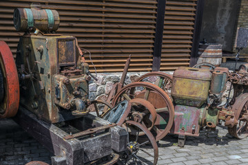 Old, rusty agricultural machinery of the last century, standing near the hangar.