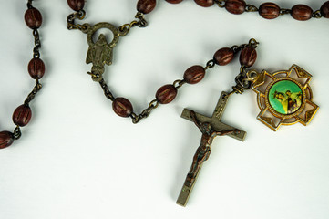 Closeup Jesus Christ crucifix and rosary with brown beads isolated on white background.