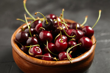 Ripe cherries in a wooden bowl on a black stone table. Red  berries on a dark background