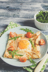 Crepes with eggs, cheese, arugula leaves and tomatoes. Galette complete. Traditional dish galette sarrasin.