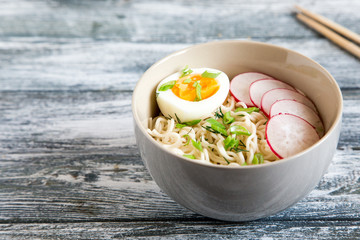 Instant noodles on wooden background. Cooked chinese instant noodles. Soup Ramen with egg and radish.