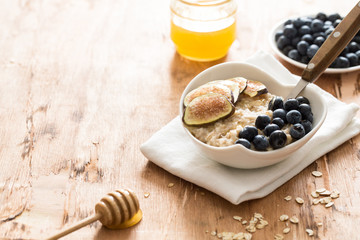 white Bowl of oats porridge figs and blueberries. Healthy oatmeal breakfast