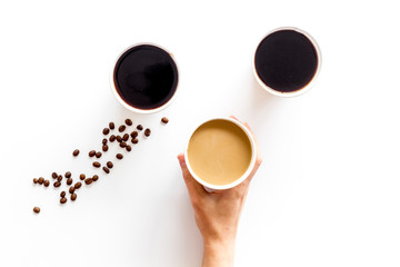 Beans, black coffee and coffee with milk to-go in hands on white background top view