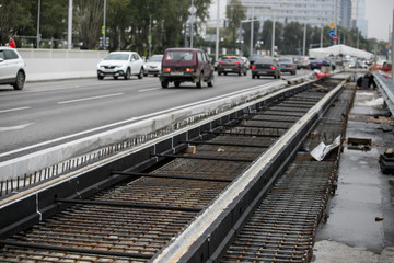 Fototapeta premium Repair of the railway tram line. Installation of new modern silent railway rails for trams. Laying of stone paving, road paving slabs on street. Repair of reconstruction of city roads with a tram line