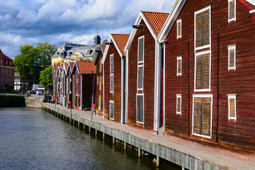 Hudiksvall, Sweden People sitting among old fishermen boathouses on the Sundskanalen, or Sund...