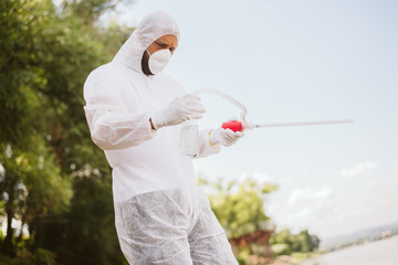 A scientist in protective clothing with a mask on his face examines the poisonous water